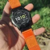 Orange HEMSUT nylon QuickFit watch band installed on a Garmin watch outdoors