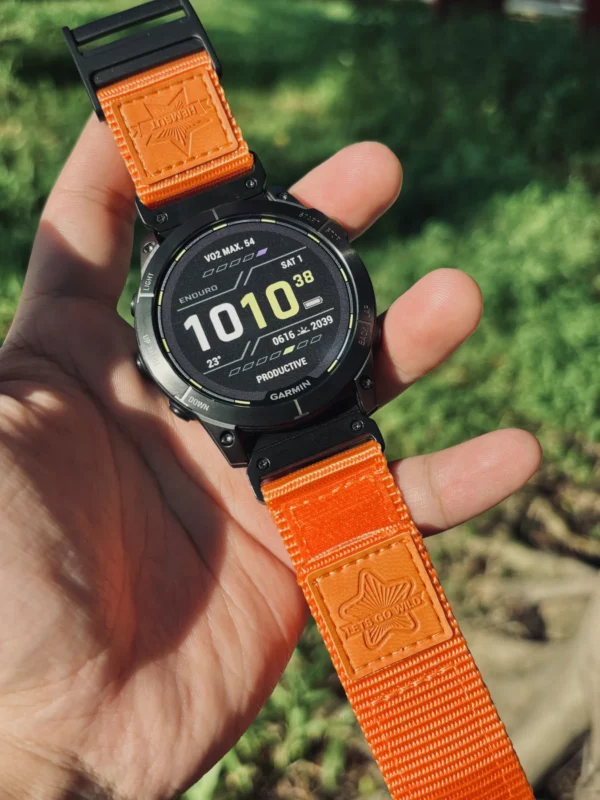 Orange HEMSUT nylon QuickFit watch band installed on a Garmin watch outdoors